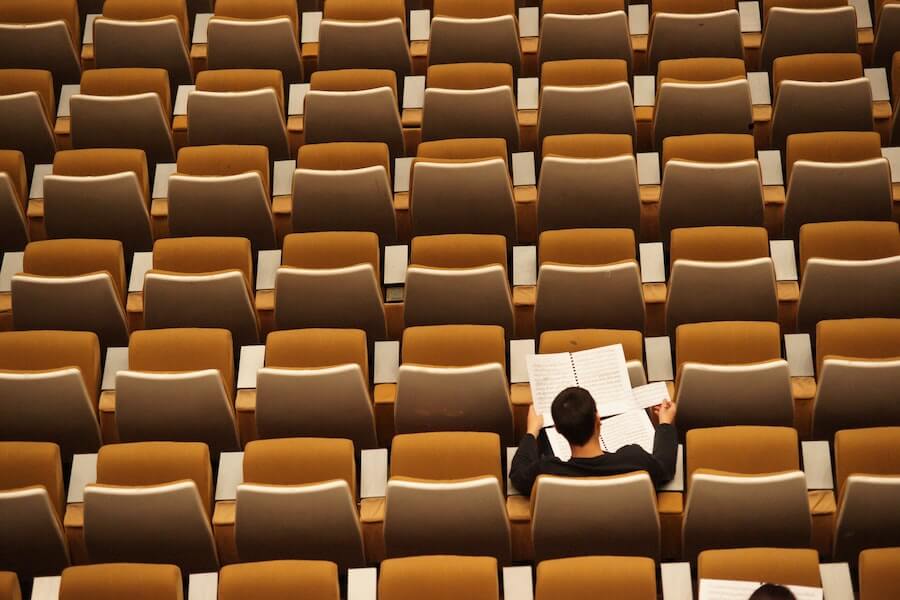 student reading notes in auditorium